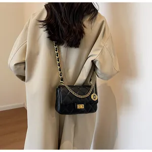 Dettaglio di una borsa a catena a rombi trapuntata nera con hardware in metallo oro.