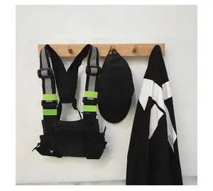Bolso de pecho táctico negro techwear con tiras reflectantes colgado en un soporte de pared