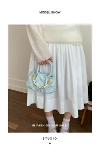 Lifestyle view of a light blue pleated cloud handbag with decorative bead handle