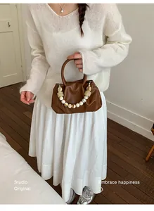 Brown pleated cloud handbag styled with a white sweater for a chic commute look