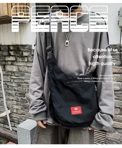 Close-up of oversized black functional messenger bag worn by a male model