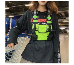 Detail view of neon green techwear chest rig bag with multiple pockets on a model