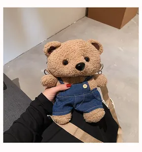 Detailed view of a cute plush teddy bear crossbody bag wearing tiny denim overalls.
