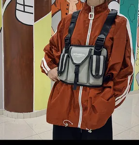 Vista de detalle de un bolso de pecho táctico gris sobre una chaqueta hip-hop naranja.