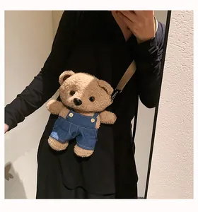 Cute 3D plush teddy bear crossbody bag wearing blue overalls in a mirror selfie view