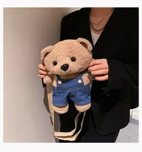 Cute small brown plush teddy bear crossbody bag wearing blue denim overalls for women