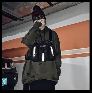 Primer plano del bolso de pecho táctico negro con tiras reflectantes estilo techwear.