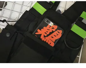Detail of black tactical chest bag with neon green reflective straps and phone pocket