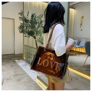 Bolso tote transparente marrón con aplique LOVE y bolsa interior mostrado en modelo.