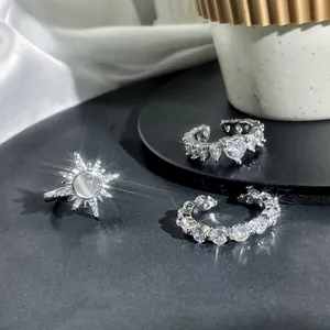 Close-up of silver starburst and heart open rings set with sparkling cz details