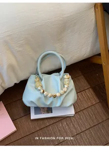 Macro view of light blue pleated cloud handbag featuring decorative marble-style beads
