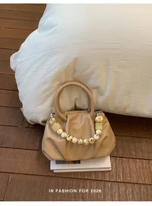 Close-up view of beige pleated cloud bag featuring an elegant marble bead handle