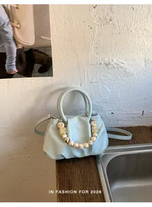 Detail view of stylish light blue pleated cloud handbag with unique marble bead chain strap