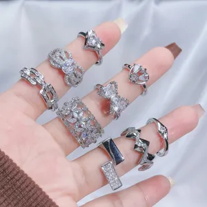 Detailed view of multiple silver-toned open rings with rhinestones on fingers.