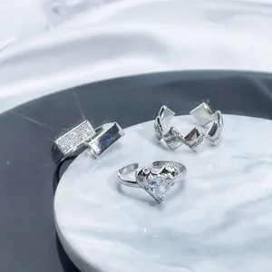 Close-up of three silver adjustable rings with shimmering heart and geometric diamonds.