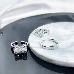 Detailed view of elegant silver-colored open rings featuring crystal heart and bow designs