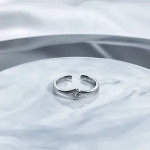 Close-up of a minimalist silver open ring featuring a sparkling star-shaped setting