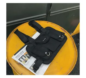 Detailansicht einer schwarzen taktischen Brusttasche mit funktionellen Taschen auf Gelb