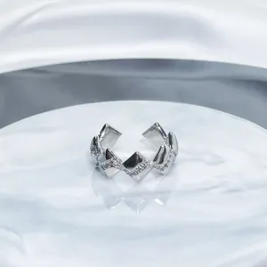 Close-up detail of a silver geometric open ring with shimmering pavé-set stones.
