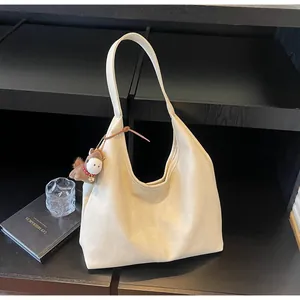 Λεπτομέρεια κρεμ ρετρό τσάντας tote με γούρι αλόγου, τοποθετημένη σε σκούρο ράφι.