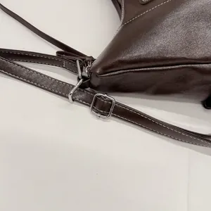 Dettaglio della fibbia d'argento e cuciture bianche su borsa in pelle marrone