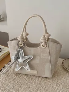 Trendy cream woven canvas tote bag featuring dual knotted handles and starfish charm