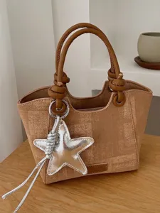 Stylish minimalist tan woven handbag featuring silver star charm and top handles