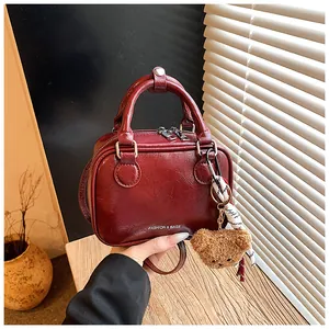 Nahaufnahme einer modischen roten Kunstleder-Boxtasche mit niedlichem Plüschbär-Anhänger.