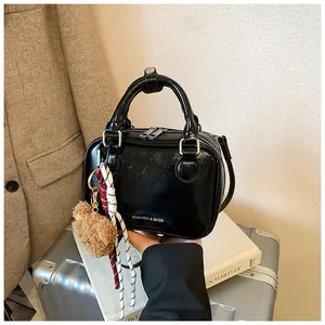 Nahaufnahme einer schwarzen Boston-Tasche mit glänzender Textur und süßem Bärenanhänger