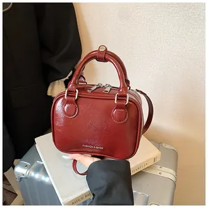 Nahaufnahme einer modischen roten glänzenden Box-Tasche mit Henkel und Gurt