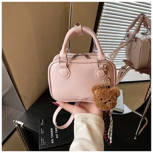 Detail einer kleinen rosa Handtasche aus Leder mit einem süßen Plüschbär-Anhänger