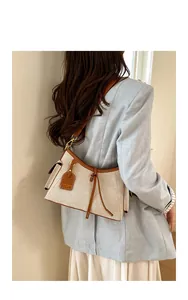 Elegante bolso de hombro de lona para mujer con detalles en cuero marrón en una modelo