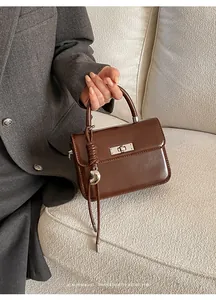 Detailed shot of brown faux leather square handbag with silver turn-lock and heart charm