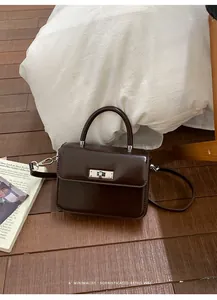 Detailed view of a stylish dark brown glossy small square bag with silver lock closure