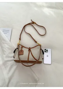 Bolso de lona y cuero mostrado junto a un smartphone para referencia de tamaño