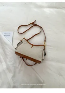 Detalle de un bolso bandolera minimalista de lona beige con ribete de cuero marrón en tela