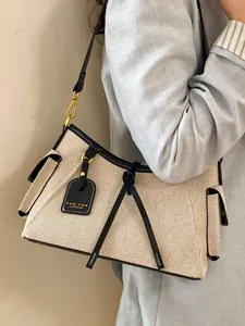 Elegante bolso de lona para mujer con ribete de cuero negro y detalles en metal dorado