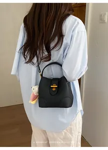 Modella che indossa una borsa a tracolla nera in pelle con chiusura a scatto dorata.