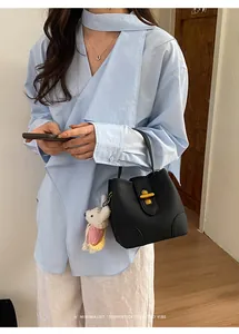 Un'elegante borsa a mano in pelle nera tenuta da una donna con una camicia blu chic.