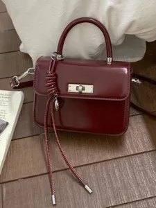 Elegant burgundy square handbag with silver turn-lock and tassel detail.