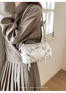 Detail view of a white vintage-style pillow bag with silver zippers and D-rings.