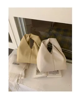 Close-up of minimalist pleated leather handbag in beige and yellow tone