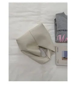 Detail view showing the soft pebbled leather texture of the cream pleated handbag.