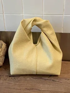 Minimalist light yellow pleated leather handbag with a unique twisted knot handle