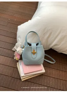 Borsa a secchiello in pelle celeste con chiusura dorata e ciondolo a forma di coniglio