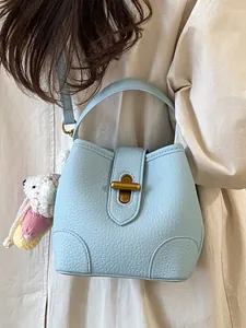 Borsa a mano in pelle martellata celeste con chiusura girevole dorata e ciondolo a coniglio