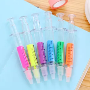 Macro view of colorful syringe-shaped highlighters with ml scales on a blue notebook