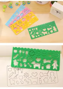 Close-up view of a green plastic drawing stencil showing emoji and animal hollowed shapes