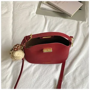 Elegante rode zadeltas crossbody met gouden hardware en een pluche beer bedeltje