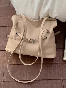 Bolso tote beige grande y relajado con detalle de hebilla en un suelo de madera oscura